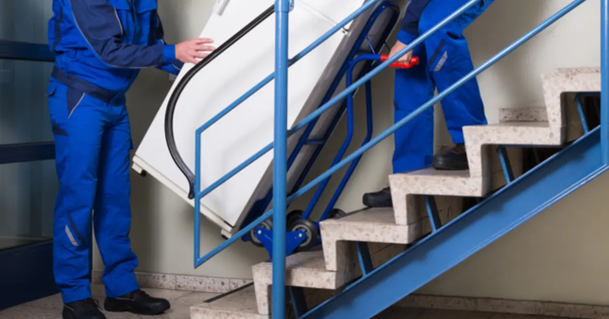 movers using a dolly truck to safely move a fragile household article on the staircase